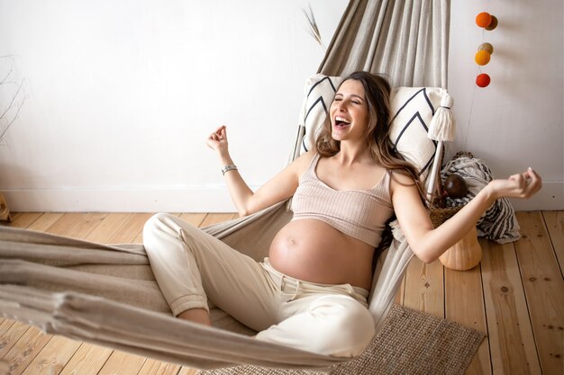 Pregnant girl lying in a hammock meditates and rejoices in her condition concept happy pregnancy