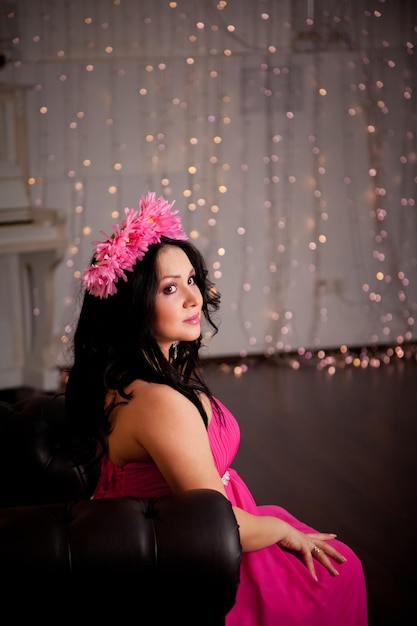 Pregnant girl in a pink dress with flowers in her hair