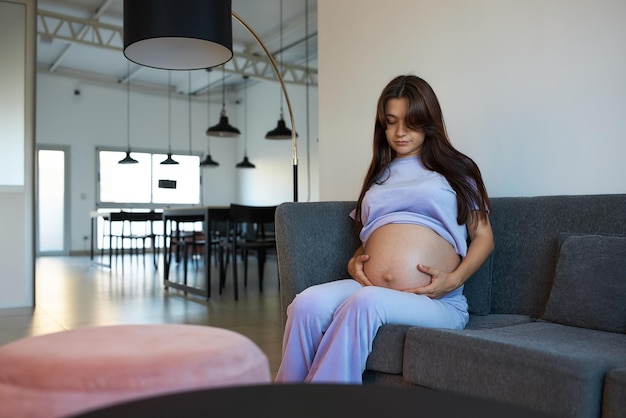 Pregnant girl sitting on couch in spacious room meeting room