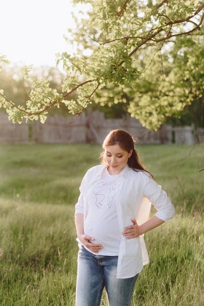 Pregnant girl in summer outdoors in the setting sun