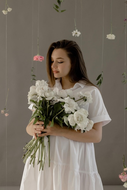 Ragazza incinta in un vestito bianco con peonie