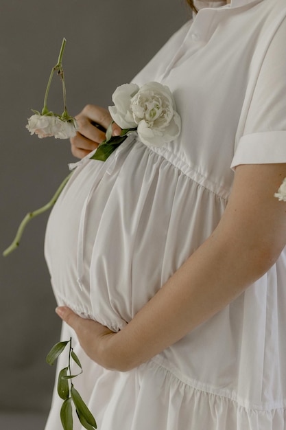 Pregnant girl in a white dress with peonies