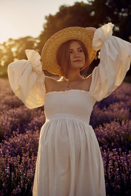 The pregnant girl with a hat in the lavender field on a sunset