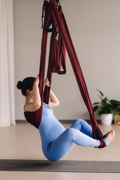 Pregnant girl A woman does yoga on a hammock in the gym The concept of a healthy lifestyle Motherhood