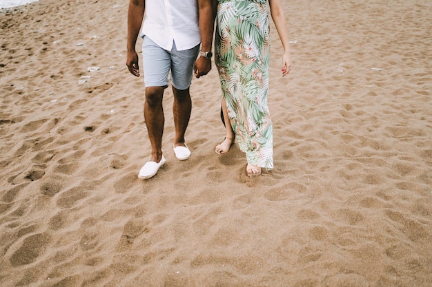 A pregnant interracial couple walking on the beach