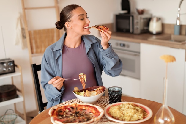 妊婦が居心地の良いキッチンでピザとパスタを楽しんでいます