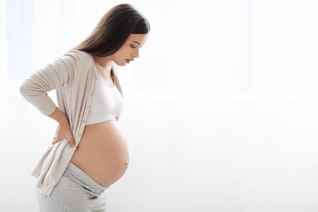 Pregnant lady having back pain over white background