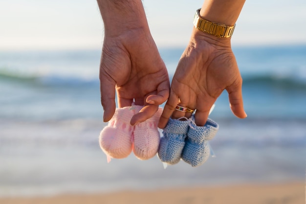 Pregnant maternity latin woman on the beach at sunset maternity concept Detail of the blue and pink booties