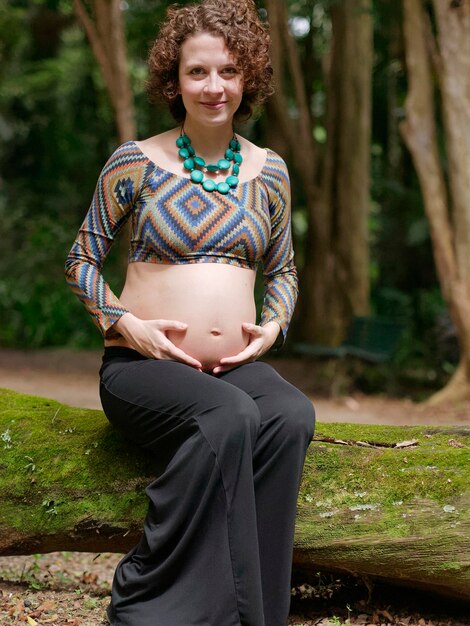 Pregnant modern young woman touching her belly outdoors