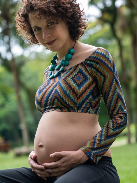 Foto giovane donna moderna incinta che tocca la sua pancia all'aperto