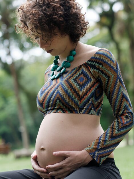 Pregnant modern young woman touching her belly outdoors.