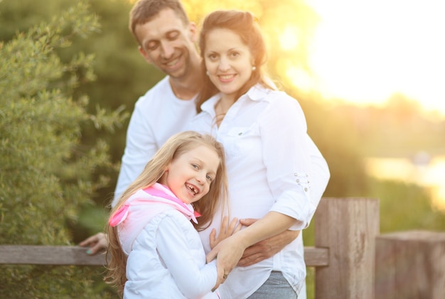 Pregnant mom,happy father and little daughter on a walk in the Park on a Sunny day.