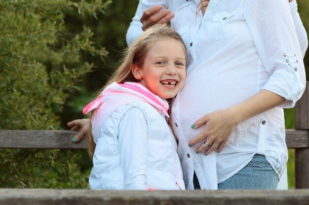 Pregnant mom,happy father and little daughter on a walk in the Park