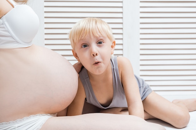 Foto mamma incinta e ragazzo biondo sorpreso.