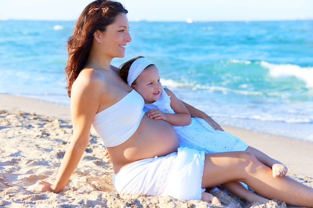 Pregnant mother and daughter on the beach