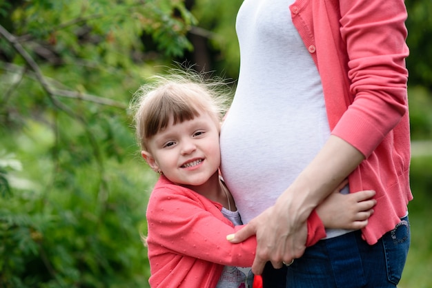 A pregnant mother and daughter outdoors