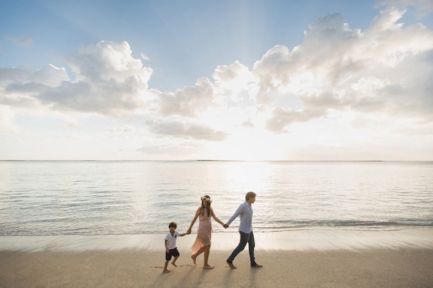 Pregnant mother, father and son walking on the beach