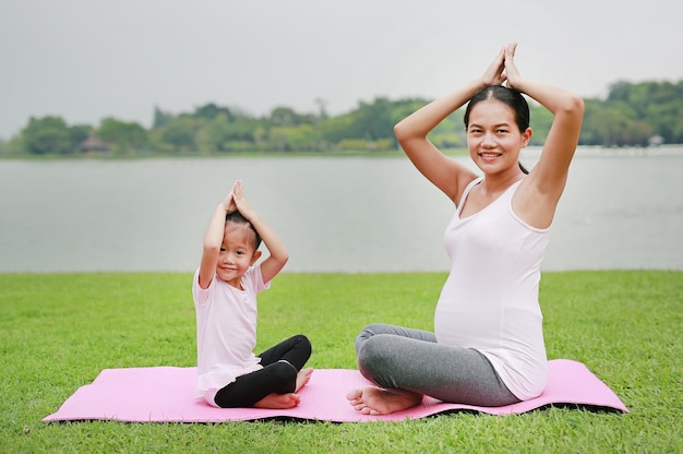 Pregnant mother and her daughter doing yoga 