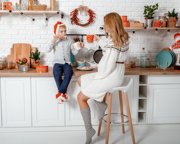 Pregnant mother and her son enjoying in kitchen and christmast time. Pregnant woman with son on New Year's holidays.