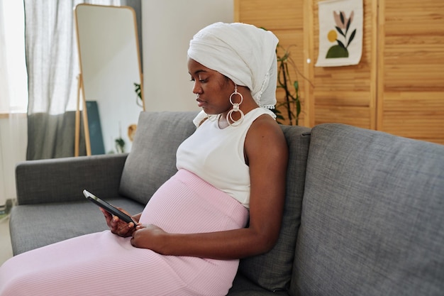 Donna musulmana incinta che usa il suo telefono