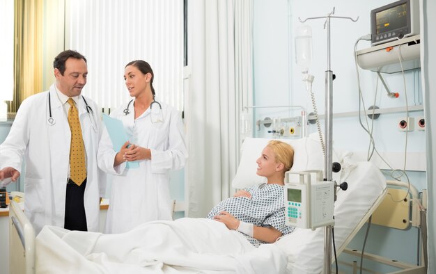 Pregnant patient in her bed talking with doctors