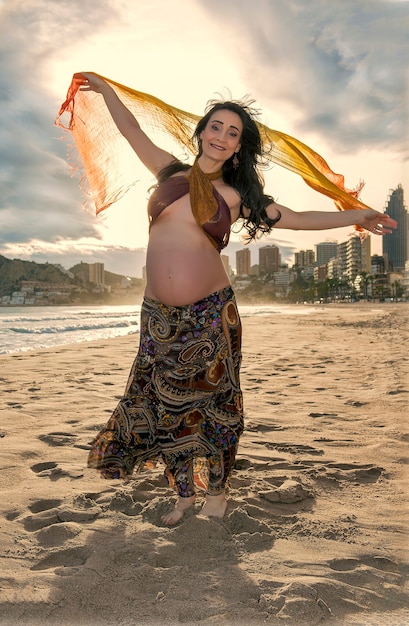 Pregnant posing on lonely beach at sunset