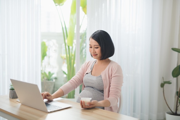 pregnant positive woman eating jogurt in the livingroom