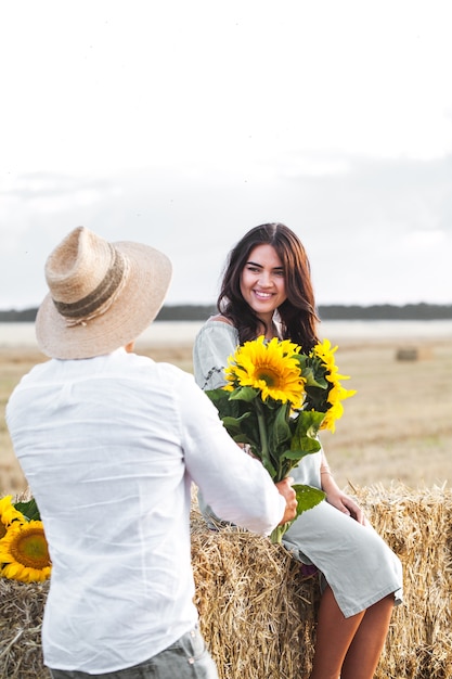 Pregnant with her husband in the manger. Beautiful couple with sunflowers