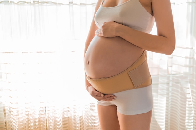 беременная с ортопедическим поясом поддержки против боли в спине на беременной женщине без окна концепция ортопедического пояса поддержки