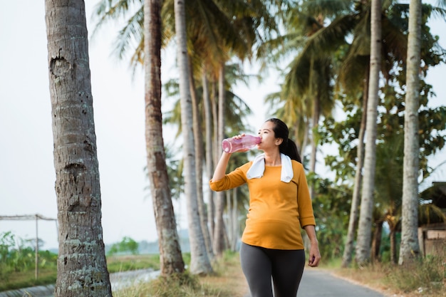 水のボトルを飲んでトレーニングの後の妊娠中の女性