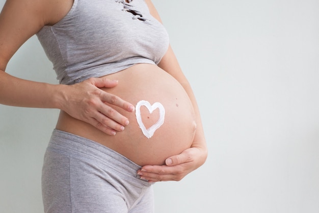 A pregnant woman applies stretch marks cream to her stomach. Stretch marks. Striae. Moisturize the skin during pregnancy. Body skin care. Pregnancy. Maternity.