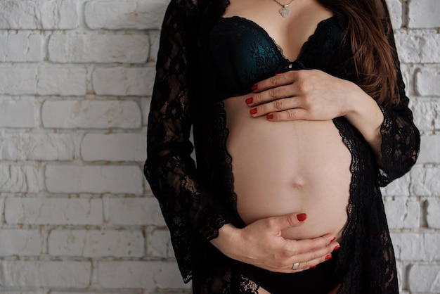 Pregnant woman in black bodysuit holding her belly