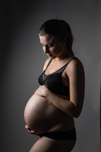 Pregnant woman black clothes dark background