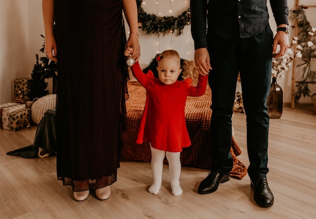 Donna incinta in abito lungo nero con il marito in abito formale nero con bambino in abito rosso. mattina di natale. interni di capodanno. celebrazione di san valentino