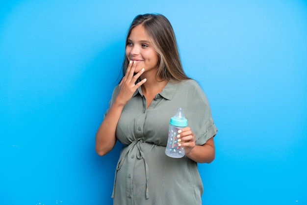 Беременная женщина на синем фоне смотрит вверх, улыбаясь