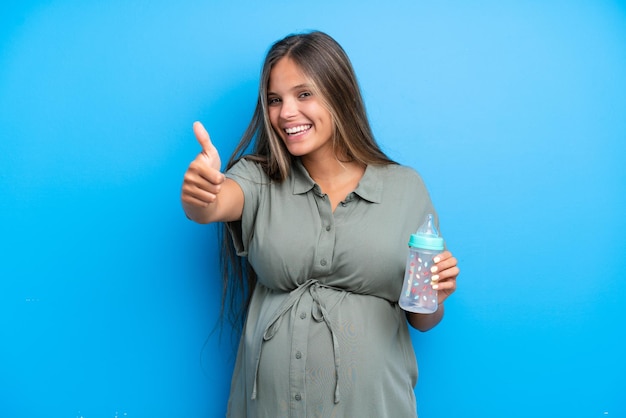 Pregnant woman on blue background with thumbs up because something good has happened