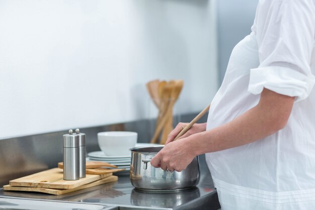 妊娠中の女性が食べ物を準備する台所で忙しい