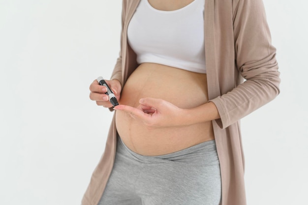 Photo pregnant woman checking blood sugar level by using digital glucose meter