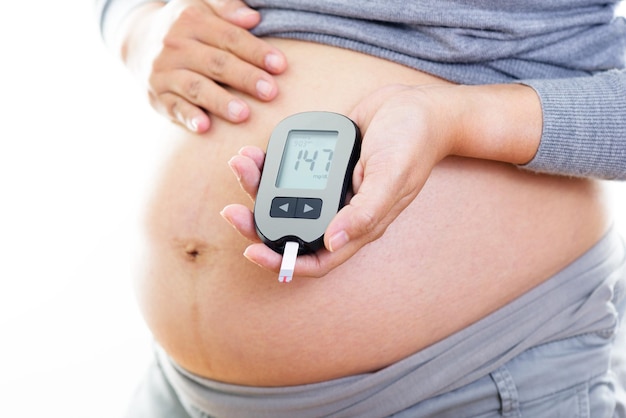 Pregnant woman checking blood sugar level with blood glucose meter Gestational diabetes