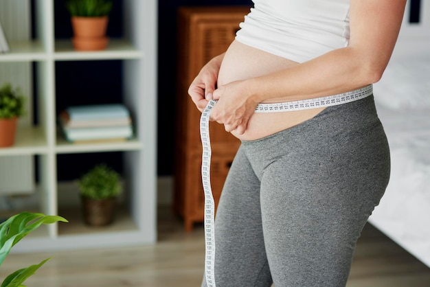 Pregnant woman checking the measure of the abdomen