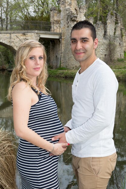 Photo pregnant woman couple man standing on green park garden on background nature