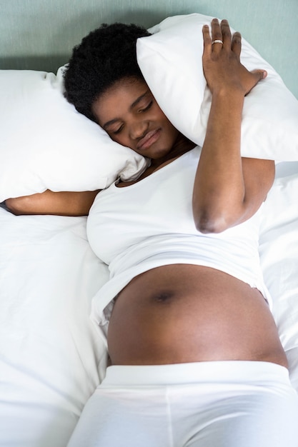 妊娠中の女性が枕で彼女の耳を覆っています