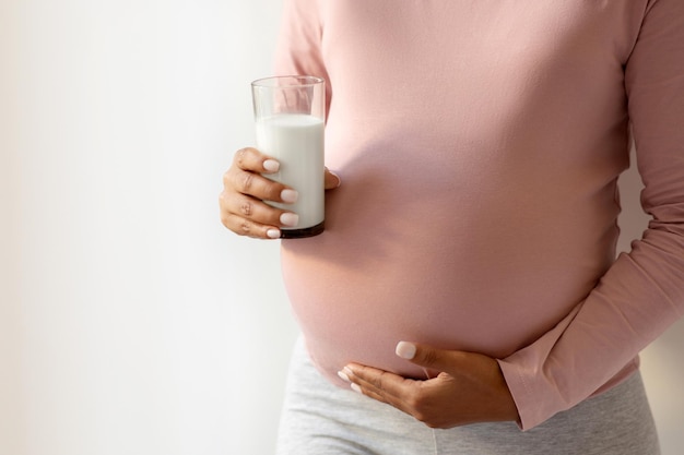 Pregnant woman cradling her belly and holding glass of milk