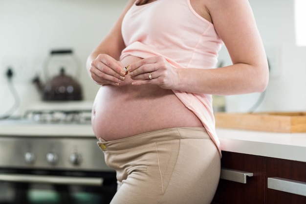 Pregnant woman destroying cigarette in kitchen 