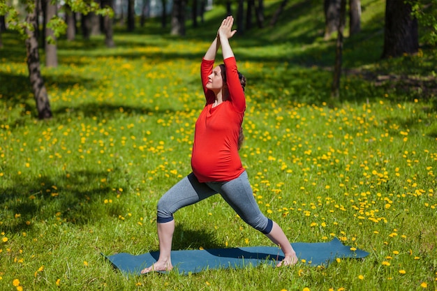 Pregnant woman doing asana outdoors