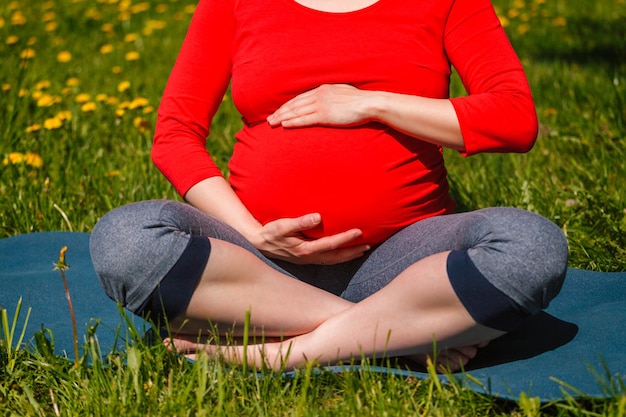 Foto donna incinta che fa asana sukhasana all'aperto