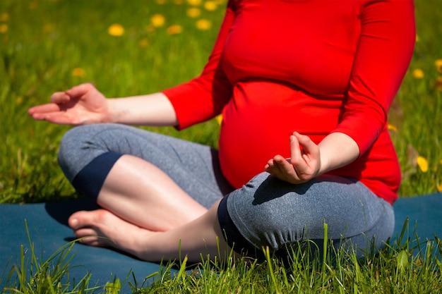 Pregnant woman doing asana sukhasana outdoors