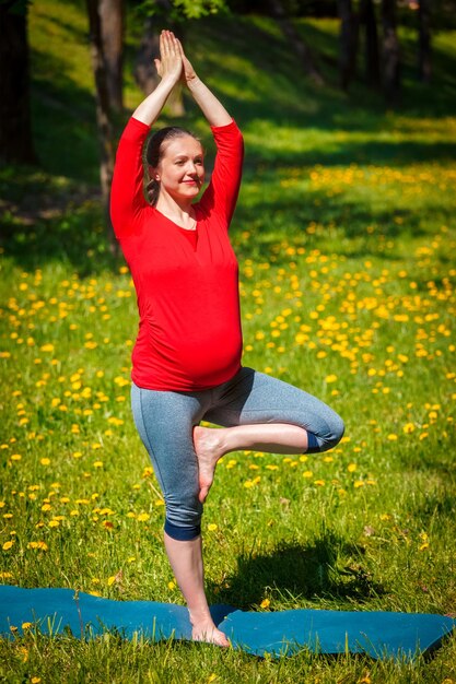 Photo pregnant woman doing asana vrikshasana outdoors