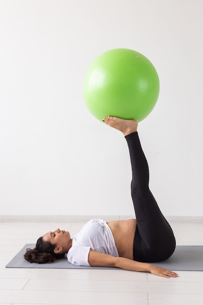 Pregnant woman doing gymnastics on rug on the floor on white