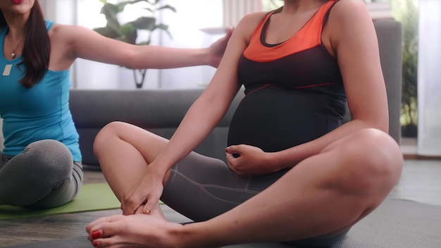 Pregnant woman doing pilates exercise with personal trainer at home.